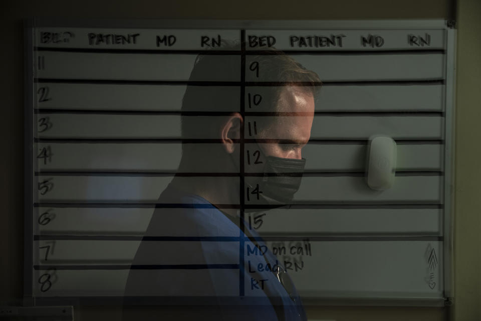 In this photo created with an in-camera multiple exposure, registered nurse Verlin Frazier, part of a group of nurses who had been treating coronavirus patients in an intensive care unit, stands for a photo in front of a patient board in the empty COVID-19 ICU at Providence Mission Hospital in Mission Viejo, Calif., Tuesday, April 6, 2021. Frazier still remembers watching a woman walk between RotoProne beds to reach — and say goodbye to — her husband. "I remember biting my tongue and cheek, holding my breath, anything to prevent myself from bursting into tears," says Verlin. (AP Photo/Jae C. Hong)