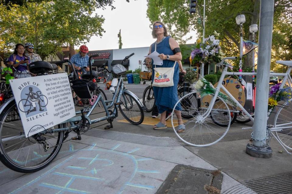 Deb Banks, the executive director of Sacramento Area Bicycle Advocates, reads a message from the family of Kate Johnston, who was killed while riding her bike to work at 21st and X streets in midtown Sacramento, next to a ghost bike during a “Ride of Silence” event on Wednesday.