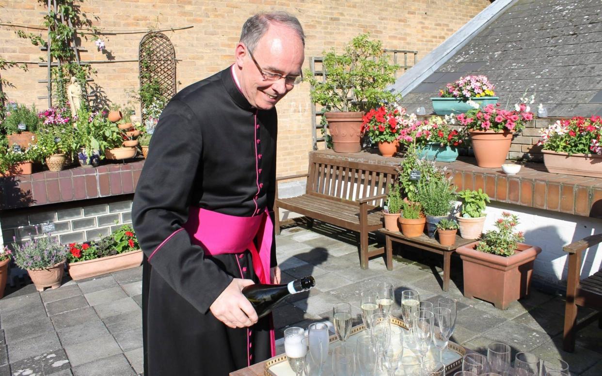 Father Langham pouring prosecco at the Fisher House terrace in Cambridge, 2016