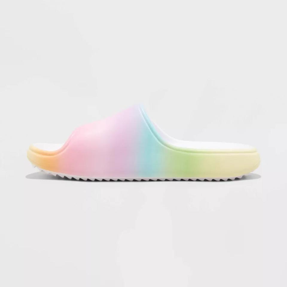 A single, rainbow-colored slide sandal with a ridged sole is displayed against a plain background