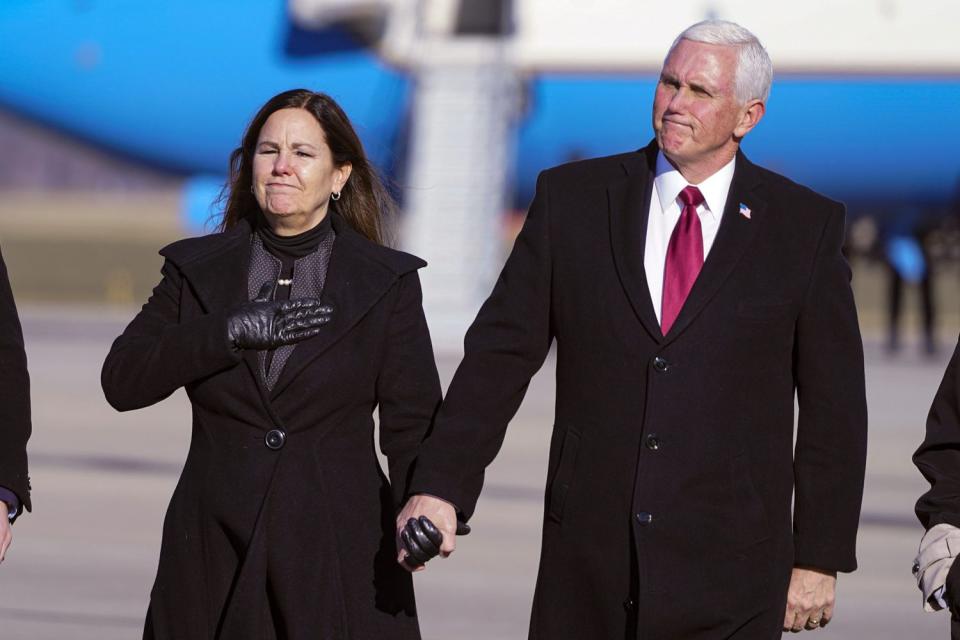 Former Vice President Mike Pence and his wife Karen walk from the plane to greet supporters after arriving back in his hometown of Columbus, Ind