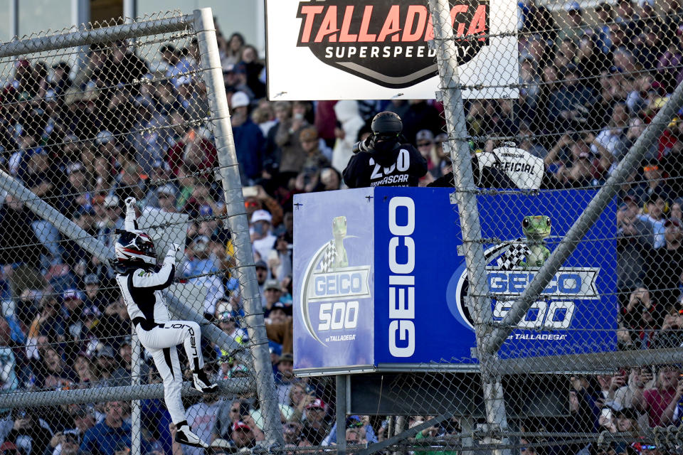 Tyler Reddick celebrates his win and climbs a fence at a NASCAR Cup Series auto race at Talladega Superspeedway, Sunday, April 21, 2024, in Talladega. Ala. (AP Photo/Mike Stewart)