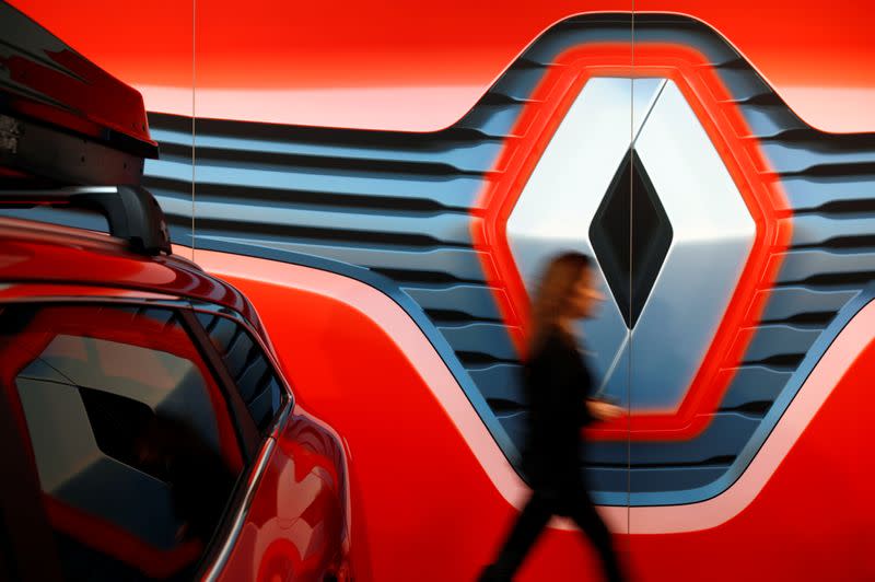 Employee walks in front of the displayed logo of Renault carmaker at a dealership in Saint-Herblain