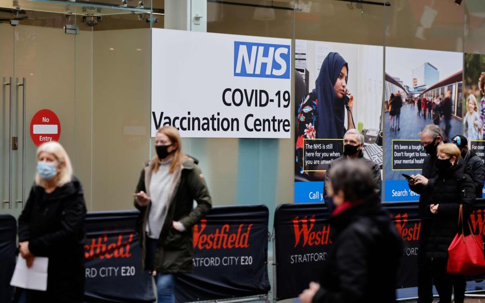 People queue to enter an NHS Covid-19 vaccination centre - Tolga Akmen / AFP