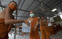 Thai Buddhist monks wearing face masks to protect themselves from the coronavirus pass pack of water after their devotees donated water to Molilokayaram temple in Bangkok, Thailand, Friday, April 17, 2020. (AP Photo/Sakchai Lalit)