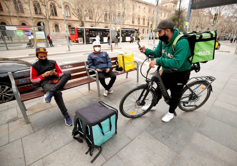 FILE PHOTO: FILE PHOTO: Delivery riders with backpacks of Glovo, Uber eats and Deliveroo wait for orders at Universitat square in Barcelona