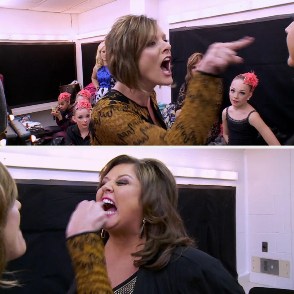 Dance instructor Abby Lee Miller angrily gestures and speaks in a dressing room with young dancers in the background