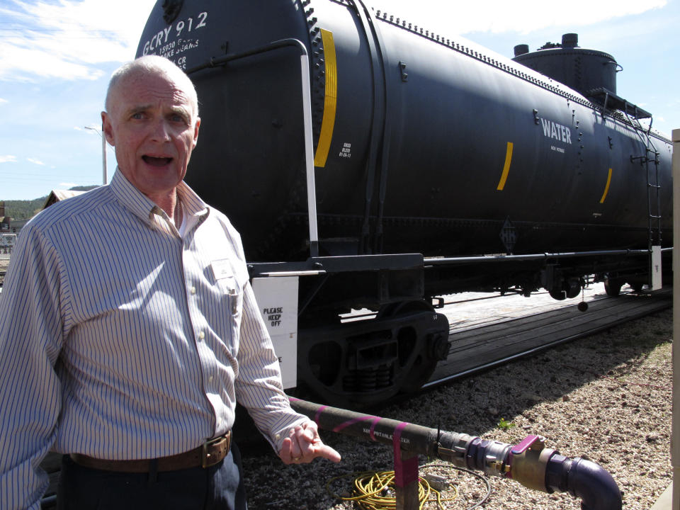 In this April 11, 2014 photo, Grand Canyon Railway train operations general manager Bob Baker poses with the rail cars that are storing water for use on the property in Williams, Ariz. Officials in Williams have declared a water crisis amid a drought that is quickly drying up nearby reservoirs and forcing the community to pump its only two wells to capacity. (AP Photo)