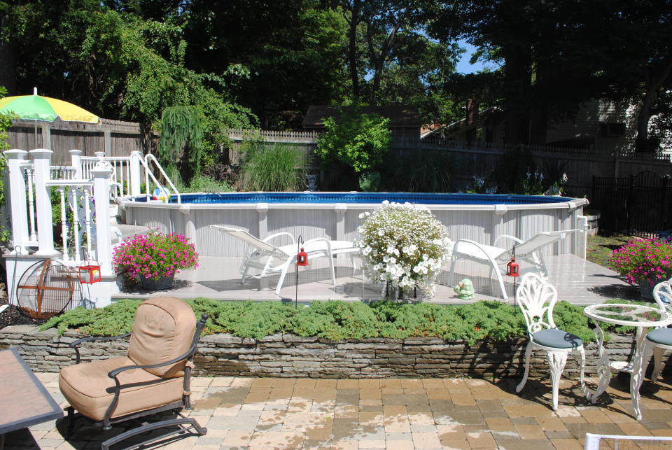 Large circular above-ground pool with a white surround, pool deck, and raised garden bed