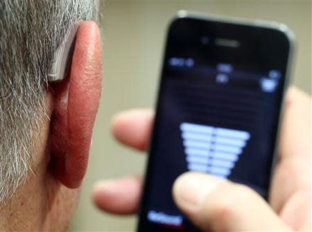 An employee of GN, the world's fourth largest maker of hearing aids, demonstrates the use of ReSound LiNX in Vienna November 22, 2013. REUTERS/Heinz-Peter Bader