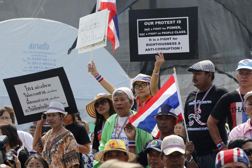 In this photo taken Monday, Jan. 27, 2014, protesters watch high level police officers leave after pleading with a monk protest leader to leave the neighboring government building to Bangkok, Thailand. Some government officials have resorted to pleading with protests occupying their government offices where daily functions such as passport controls and immigration issues are backing up. (AP Photo/Wally Santana)