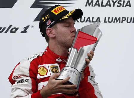 Ferrari's Sebastian Vettel celebrates winning the Malaysian Grand Prix with the trophy on the podium. Reuters / Olivia Harris