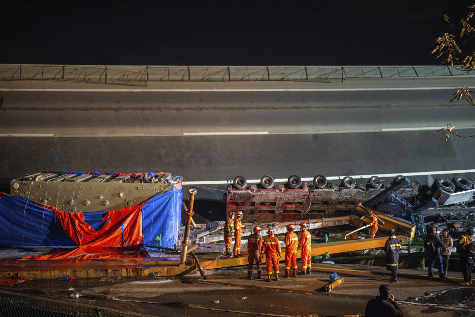 In this photo released by Xinhua News Agency, rescue workers stand near vehicles at the site of ramp bridge collapse in Ezhou, central China's Hubei Province on Saturday, Dec. 18, 2021. Some were killed and injured after part of the ramp bridge in the city of Ezhou, central China's Hubei Province, collapsed on Saturday afternoon, according to local authorities (Wu Zhizun/Xinhua via AP)