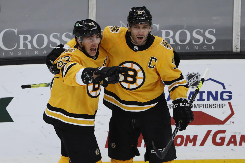 Boston Bruins' Patrice Bergeron, right, celebrates with Brad Marchand, left, after Marchand scored against the Pittsburgh Penguins during the second period of an NHL hockey game Saturday, April 3, 2021, in Boston. (AP Photo/Winslow Townson)