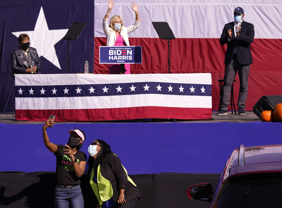 While maintaining social distance, people try to make a selfie as Jill Biden, center, waves to supporters after she was introduced by Rep. Eddie Bernice Johnson, D-Texas, left, with Rep. Marc Veasey, D-Texas, looking while campaigning for her husband and former Vice President Joe Biden in a parking lot event at Fair Park Tuesday, Oct. 13, 2020, in Dallas. (AP Photo/LM Otero)