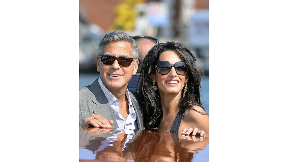 US actor George Clooney ( L) and his Lebanon-born British fiancee Amal Alamuddin take a taxiboat upon their arrival in Venice on September 26, 2014, on the eve of their wedding.    AFP PHOTO / ANDREAS SOLARO        (Photo credit should read ANDREAS SOLARO/AFP via Getty Images)