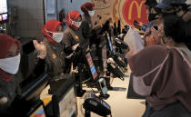 Employees wearing face masks as a precaution against the new coronavirus outbreak serve customers at a McDonald's restaurant in Jakarta, Indonesia, Sunday, May 10, 2020. (AP Photo/Dita Alangkara)