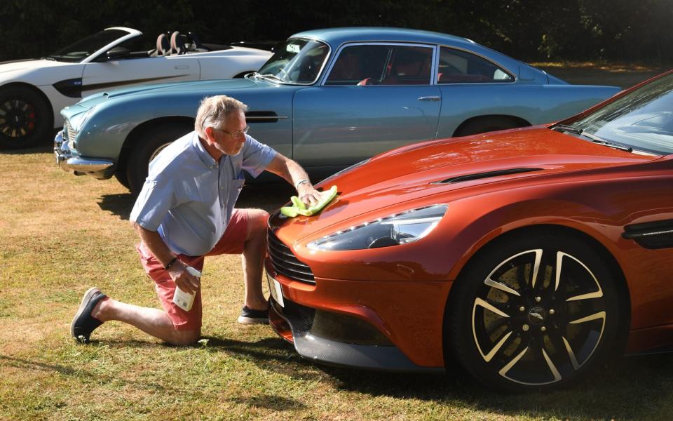 Paul Spencer from Odiham, Hampshire pristinely polishes hi uniquely cinnabar coloured 2016 Vanquish Volante in the shadow of a blue 1964 DB5 - Â©Russell Sach - 0771 882 6138