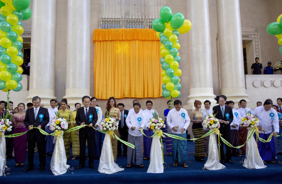 FILE - In this Dec. 9, 2015, file photo, senior government officials and foreign investors cut a ribbon during the opening ceremony of the Yangon Stock Exchange in Yangon, Myanmar. The military coup in Myanmar is unlikely to do the country’s struggling economy any good at all. The country once considered a promising last frontier has languished as the pandemic added to its challenges. (AP Photo/Gemunu Amarasinghe, File)