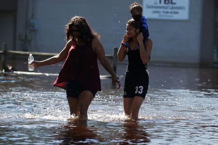 Residents walk in flood water in the aftermath of Hurricane Matthew in Lumberton, North Carolina. REUTERS/Carlo Allegri