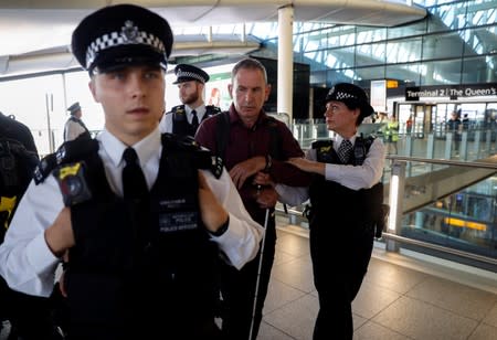 Police officers detain environmental activist James Brown at Heathrow Terminal 2, after climate change protesters tried to launch drones within the airport's exclusion zone, in London