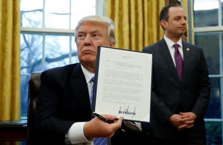 U.S. President Donald Trump holds up the executive order on the reinstatement of the Mexico City Policy after signing in the Oval Office of the White House in Washington January 23, 2017. At his side is White House Chief of Staff Reince Priebus. REUTERS/Kevin Lamarque