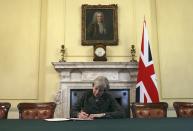 FILE - In this Tuesday March 28, 2017 file photo, Britain's Prime Minister Theresa May, sitting below a painting of Britain's first Prime Minister Robert Walpole, signs the official letter to European Council President Donald Tusk, in 10 Downing Street, London, invoking Article 50 of the bloc's key treaty, the formal start of exit negotiations. Britons voted in June to leave the bloc after four decades of membership. (Christopher Furlong/Pool Photo via AP, File)