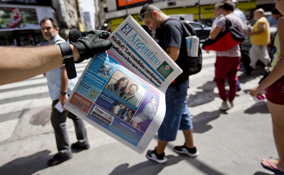 A man offers copies of "El Argentino" a free news paper, to people on Buenos Aires' Florida street with a headline, reading: "Kicillof : The exchange measures benefit the less fortunate." Referring to what the Economy minister Axel Kicillof said regarding the easing of U.S. dollar exchange rate restrictions, Argentina, Monday, Jan. 27, 2014. Argentina government announced Friday it was relaxing restrictions on the purchase of U.S. dollars. The measure would start taking effect Monday, allowing Argentines to buy dollars for personal savings. (AP Photo/Natacha Pisarenko)