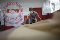 Un trabajador de la escuela de samba Unidos de Padre Miguel corta la tela para coser trajes desechables para trabajadores sanitarios durante la pandemia del coronavirus, en Río de Janeiro, Brasil, el 7 de abril de 2020. Las escuelas de samba de Río de Janeiro suelen pasar el año cosiendo frenéticamente los disfraces para el impresionante Carnaval de la ciudad. Ahora, esos ágiles dedos trabajan para proteger vidas, elaborando trajes de protección para los empleados de salud que enfrentan una oleada de pacientes con coronavirus. (AP Foto/Silvia Izquierdo)