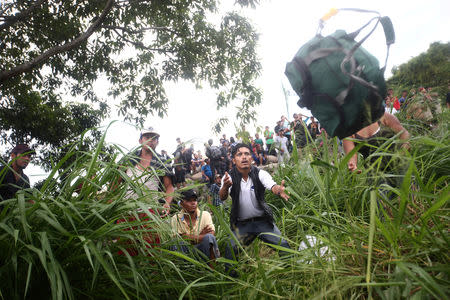 A Honduran migrant, part of a caravan trying to reach the U.S., throws a backpack after crossing the Suchiate river with the help of fellow migrants to avoid the border checkpoint in Ciudad Hidalgo, Mexico, October 19, 2018. REUTERS/Edgard Garrido