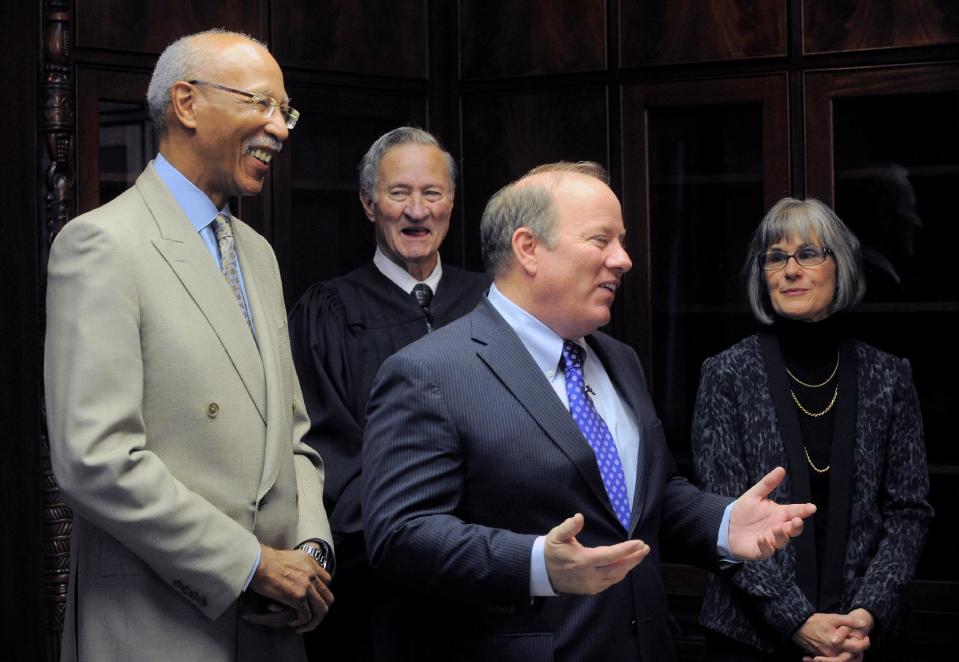 Former Detroit Mayor Dave Bing looks on as New Detroit Mayor Mike Duggan speaks with the media following the oath of office, New Years Day, Wednesday, Jan. 1, 2014, at the Coleman Young Municipal Center in Detroit. Judge Patrick James Duggan, Jr., the mayor's father and his wife Lori Maher are seen in the background. (AP Photo/The Detroit News, Steve Perez)