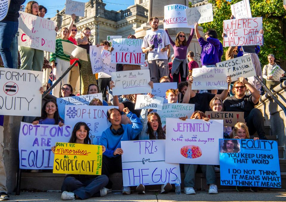 Danielle Wyng pumps her fist among community members holding signs during the rally Monday against the proposed schedule changes at MCCSC.