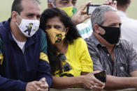 Supporters of Brazil's President Jair Bolsonaro wear face masks amid the new coronavirus pandemic decorated with his image during the president's departure from his official residence, Alvorada palace, Brasilia, Brazil, Monday, May 25, 2020. (AP Photo/Eraldo Peres)