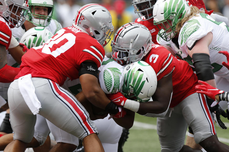 Oregon running back Travis Dye, center, is tackled by Ohio State linebackers Cody Simon, left, and Teradja Mitchell during the first half of an NCAA college football game Saturday, Sept. 11, 2021, in Columbus, Ohio. (AP Photo/Jay LaPrete)