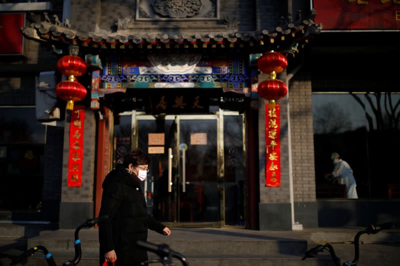 A woman wearing a face mask walks along the street as the country is hit by an outbreak of the new coronavirus, in Beijing