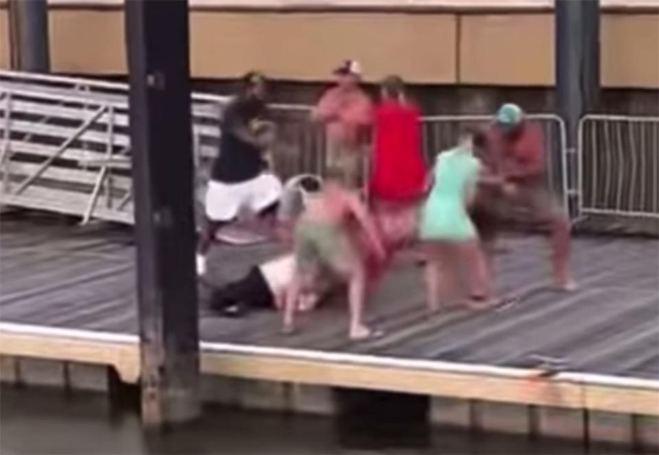 An onlooker left, rushes to help riverboat co-captain Damien Pickett, lying on the dock, against several attackers on Aug. 5, 2023, at Montgomery's Riverfront Park.