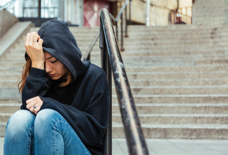 A girl looking tired and overwhelmed sitting outside on steps