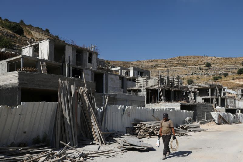A laborer walks past Israeli settlement construction sites around Givat Zeev and Ramat Givat Zeev in the Israeli-occupied West Bank