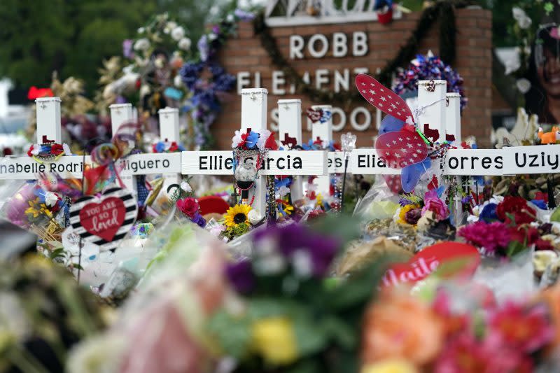 FILE – Crosses are surrounded by flowers and other items at a memorial, Thursday, June 9, 2022, for the victims of a shooting at Robb Elementary School in Uvalde, Texas. The families of 19 people who were killed or injured in the shooting and their attorneys are set to make an announcement, Wednesday, May 22, 2024. Friday will mark the two-year anniversary of the shooting where a gunman killed 19 students and two teachers. (AP Photo/Eric Gay)