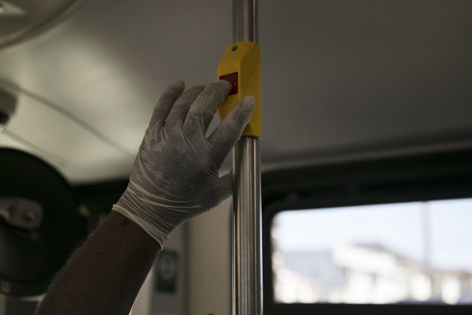 A passenger wearing a sweaty glove requests a stop in a bus during the coronavirus pandemic in the Pico-Union neighborhood of Los Angeles, Thursday, May 21, 2020. While most of California took another step forward to partly reopen in time for Memorial Day weekend, Los Angeles County didn't join the party. (AP Photo/Jae C. Hong)