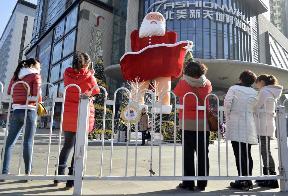 Women take pictures in front of a Santa Claus figure in Taiyuan