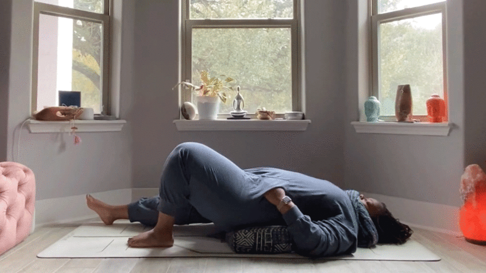 Woman lying on her back stretching her low back in her bedroom