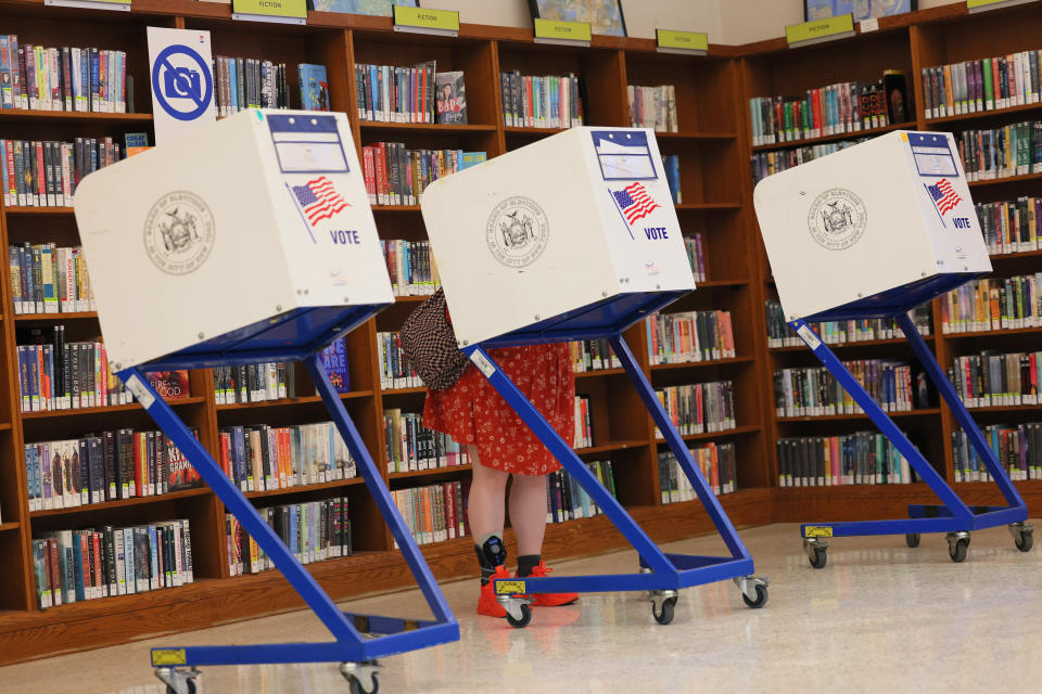 Voting machines, with a person behind one of them, in a library.