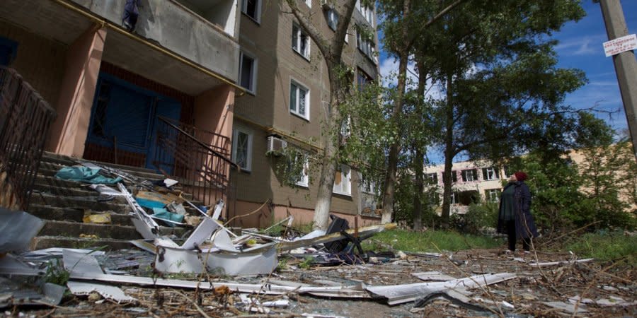 A resident of the town of Vuhledar in Donetsk Oblast next to a residential building ruined by Russian shelling