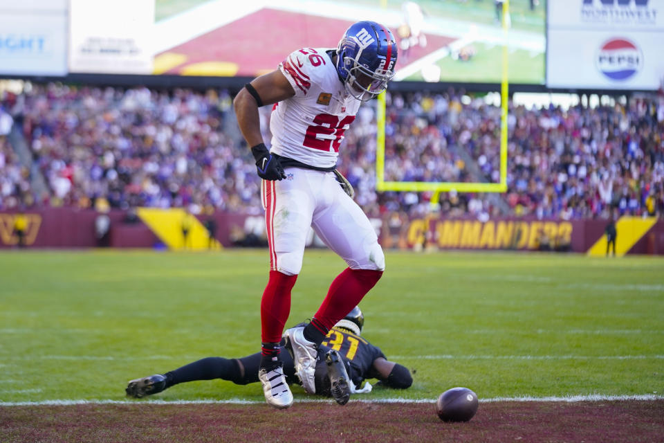 New York Giants running back Saquon Barkley (26) celebrating his touchdown against Washington Commanders safety Kamren Curl (31) during the second half of an NFL football game, Sunday, Nov. 19, 2023, in Landover, Md. (AP Photo/Andrew Harnik)