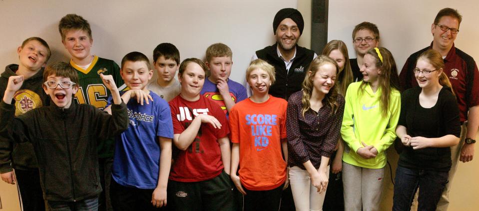 In this March 18, 2014 photo the 'Math Minions,' sixth graders at Oak Grove Middle School in Fargo, North Dakota, pose for a photo with Motif Investing founder Hardeep Walia, center right rear, and math teacher Dave Carlson, right rear, at Oak Grove Middle School in Fargo, North Dakota. Carlson started a competition between regular and advance math classes at Oak Grove and registered his students with Motif Investing, a company that enables customers to buy baskets of stocks. In the end, Carlson’s regular math class yielded a nearly 22 percent gain and trounced every university club participating in a contest that was held at the same time. (AP Photo/Bruce Crummy)