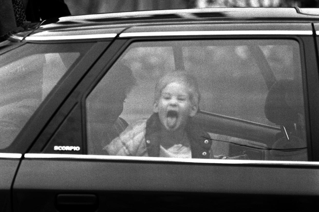 A three-year-old Prince Harry sticks out his tongue at photographers as he goes past in a car on his way to nursery