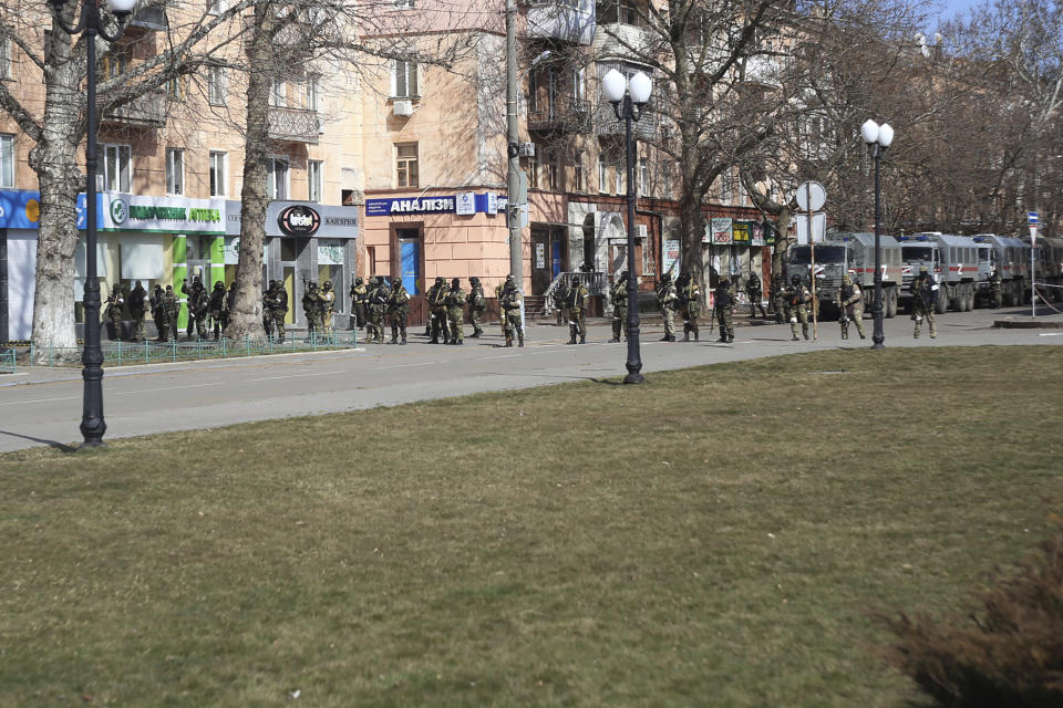 Russian troops stand in a street as people take part in a rally against the Russian occupation in Kherson, Ukraine, Monday, March 14, 2022. Ever since Russian forces took the southern Ukrainian city of Kherson in early March, residents sensed the occupiers had a special plan for their town. Now, amid a crescendo of warnings from Ukraine that Russia plans to stage a sham referendum to transform the territory into a pro-Moscow "people's republic," it appears locals guessed right. (AP Photo/Olexandr Chornyi)