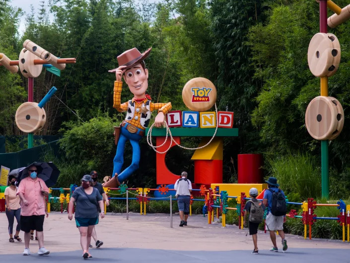 A giant Sheriff Woody leaning on the Toy Story Land Entrance with other jumbo sized wooden toys.