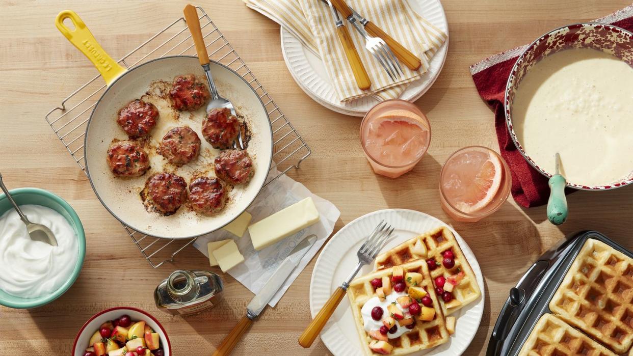 a table with sausage and waffles and grapefruit drinks